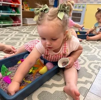 Toddler engaged in sensory bin exploration