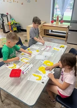 Children forming letters with playdough