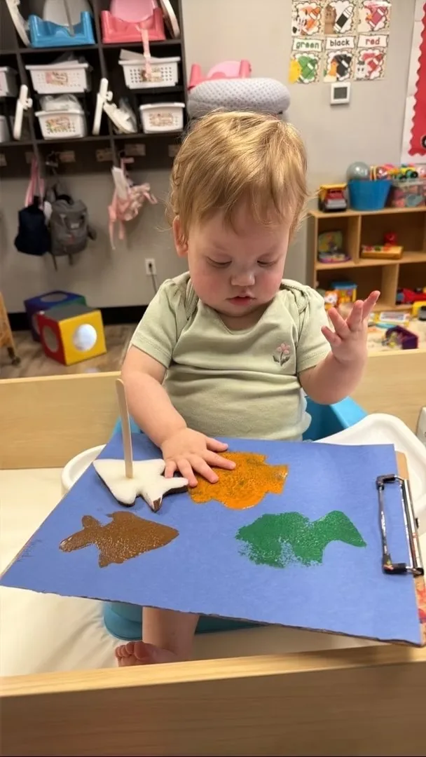 Toddler doing finger painting on blue paper